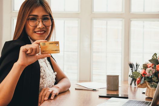 smiling asian woman with credit card for shopping online.