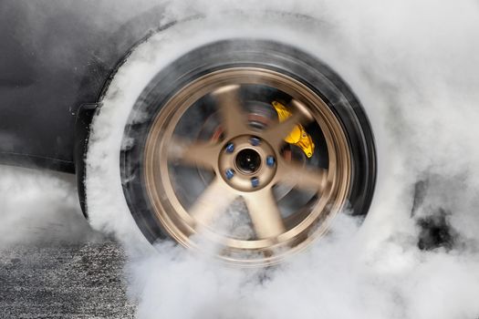 Drag racing car burns rubber off its tires in preparation for the race