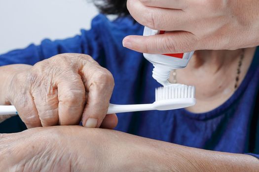 Asian elderly woman trying use toothbrush ,hand tremor . Dental health