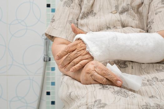 Senior woman with broken arm using the toilet with walker.