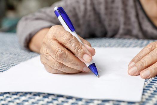 elderly woman writing on blank paper