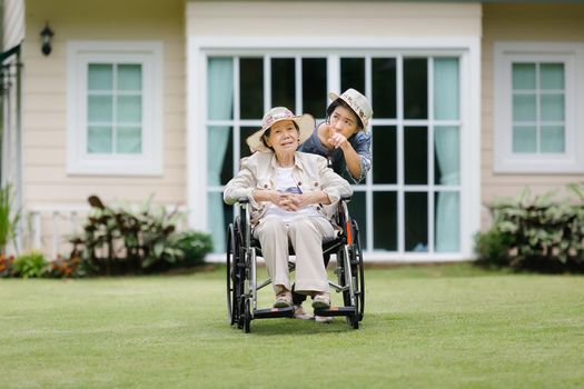 Elderly woman relax on wheelchair in backyard with daughter