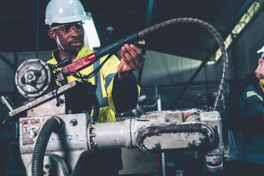 African American factory worker working with adept robotic arm in a workshop . Industry robot programming software for automated manufacturing technology .