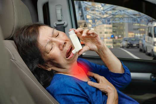 Elderly woman choking and holding an asthma spray inside car on the way.