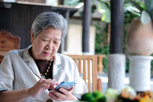 asian elder senior woman using mobile smart phone. elderly female holding cellphone. mature retirement lifestyle