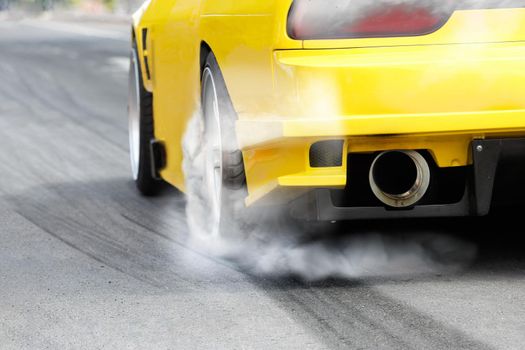 race car burns rubber off its tires in preparation for the race