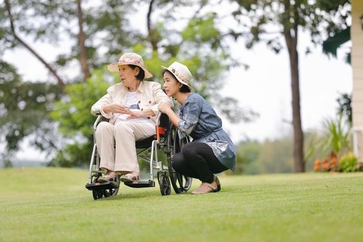 Elderly woman relax on wheelchair in backyard with daughter