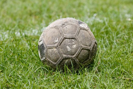 Old used football or soccer ball on field