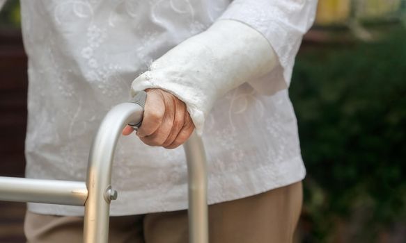 senior woman broken wrist using walker in backyard