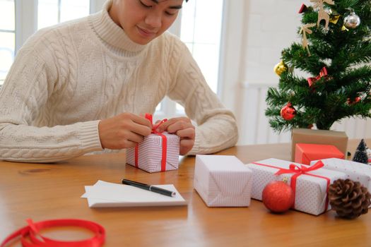 man wearing cream sweater wrapping christmas gift present box. xmas new year holiday celebration.