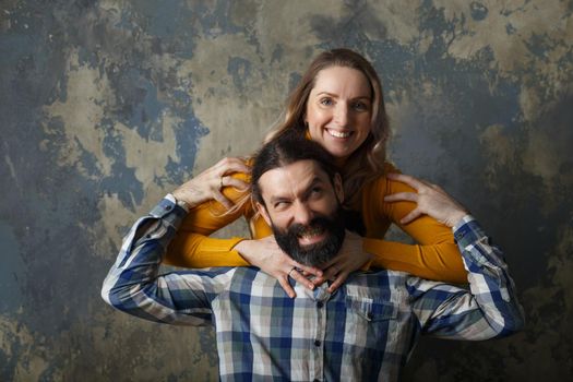 Love and relationship concept. Happy adult couple hugging, smiling wide and looking at camera, standing together on blue abstract background