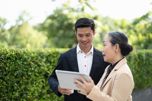 Portrait of young and senior business people working together with digital tablet outdoor