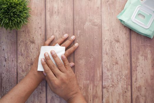 man disinfecting his hands with a wet wipe