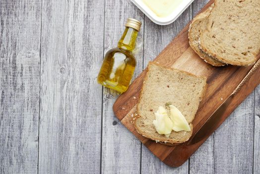 slice of butter and whole meal bread on chopping board .