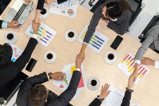 Group business people handshake at meeting table in office together with confident shot from top view . Young businessman and businesswoman workers express agreement of investment deal.