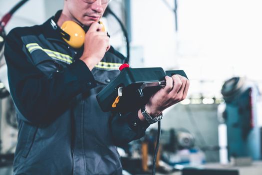 Young factory worker working with adept robotic arm in a workshop . Industry robot programming software for automated manufacturing technology .
