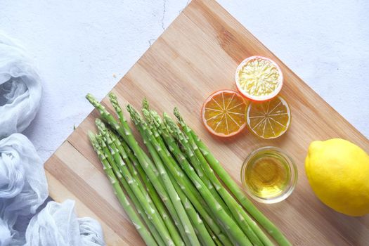 Asparagus green , lemon and oil on a chopping board , top view ,