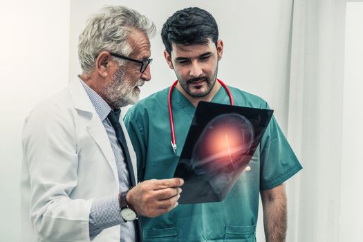 Doctor at hospital working on x ray film of patient head with another surgical doctor. Healthcare and medical staff services concept.