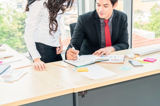 Two business people talk project strategy at office meeting room. Businessman discuss project planning with colleague at modern workplace while having conversation and advice on financial data report.