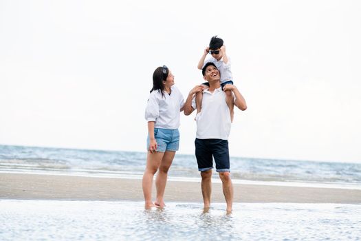 Happy family of father, mother and son goes vacation on a tropical sand beach in summer.