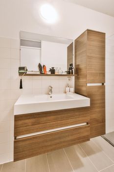 Brown cupboards and white ceramic sink ,modern appliances in the stylish bathroom