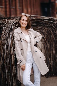 A happy stylish girl in a gray coat walks around the city.