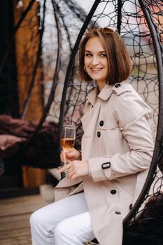 A happy stylish girl In a gray coat walks around the city.