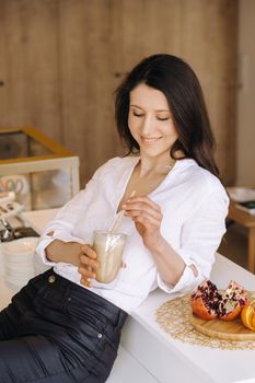 A happy healthy woman is holding a fruit cocktail in her hands, standing at home in the kitchen.Healthy eating.