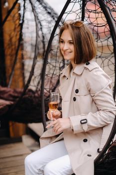 A happy stylish girl In a gray coat walks around the city.