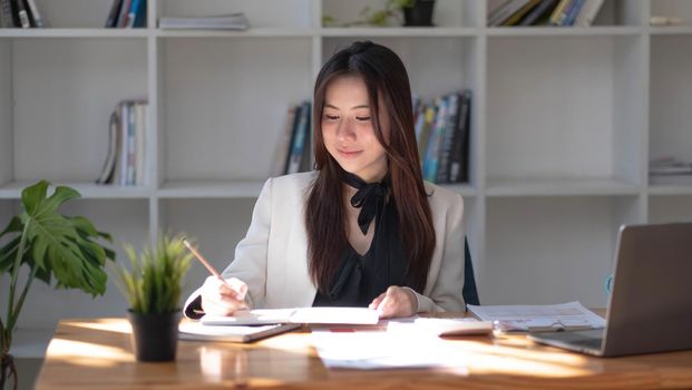 Charming asian businesswoman sitting working on laptop in office..