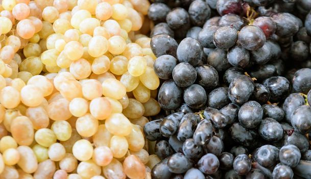Background of red, black and green grapes in a tray on the market.