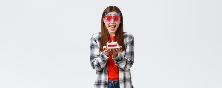 People lifestyle, holidays and celebration, emotions concept. Enthusiastic, happy birthday girl having fun on party, wear glasses and hold b-day cake, making wish over lit candle.