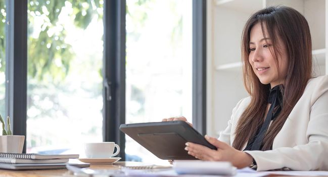 Beautiful young asian woman sitting at coffee shop using laptop. Happy young businesswoman sitting at table in cafe with tab top computer..