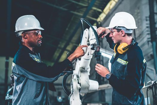 Factory workers working with adept robotic arm in a workshop . Industry robot programming software for automated manufacturing technology .
