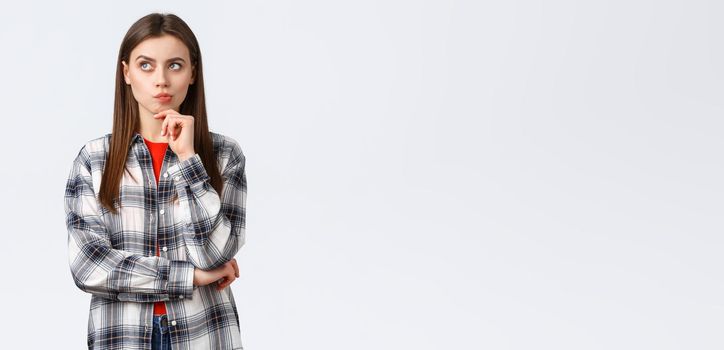 Lifestyle, different emotions, leisure activities concept. Smart woman in checked casual shirt searching solution, thinking and looking up, touch chin as pondering decision, making choice.