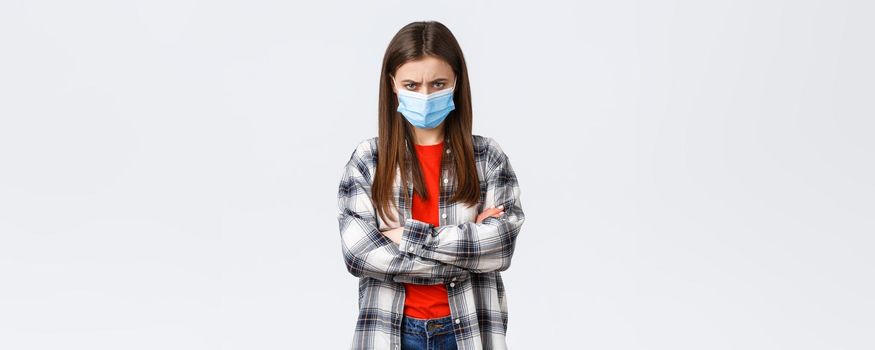 Coronavirus outbreak, leisure on quarantine, social distancing and emotions concept. Angry young mad girlfriend in medical mask and checked casual shirt, feel offended, sulking and stand defensive.