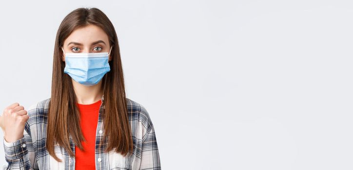 Coronavirus outbreak, leisure on quarantine, social distancing and emotions concept. Close-up of young girl in medical mask showing way, pointing thumb left at banner or information.