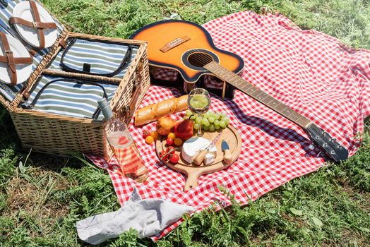 Closeup of picnic basket with drinks and food on the grass. Nice picnic on sunny summer day, fun and leisure