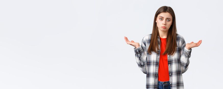 Lifestyle, different emotions, leisure activities concept. Reluctant and careless young woman shrugging with hands spread sideways, dont know, cant help, have no idea, stand white background.