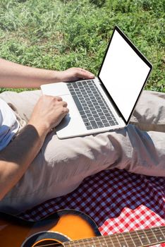 unrecognizable man in white pants outside having picnic and using laptop, working outdoors. summer leisure and fun