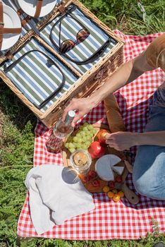 Young woman in park outside at sunny day, enjoying summertime dreaming and drinking wine. Millennial woman having picnic outdoors in sunny day