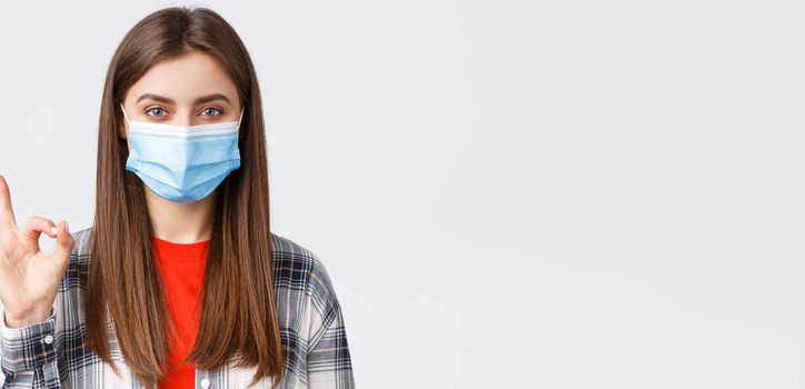 Coronavirus outbreak, leisure on quarantine, social distancing and emotions concept. Close-up of satisfied good-looking woman in medical mask, assure all good, show okay guarantee gesture.