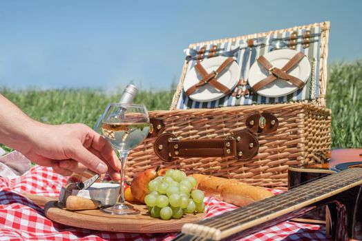 Closeup of picnic basket with drinks and food on the grass. Nice picnic on sunny summer day, fun and leisure