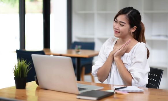 Happy young asian businesswoman sitting on her workplace in the office. Young woman working at laptop in the office..