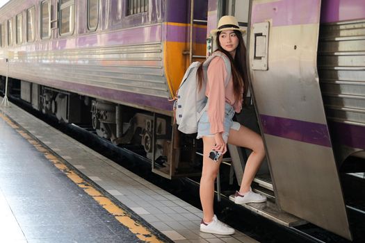 young woman tourist traveler stepping up to train on railway at train station. Travel journey trip concept