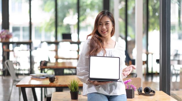 Portrait of Asian young businesses owners showing tablet with blank screen at office..