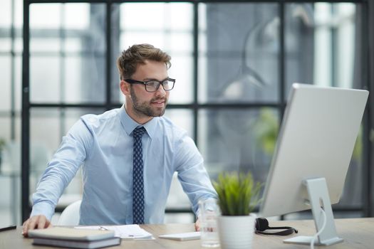 Young cheerful businessman working at office