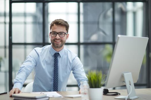 Young cheerful businessman working at office