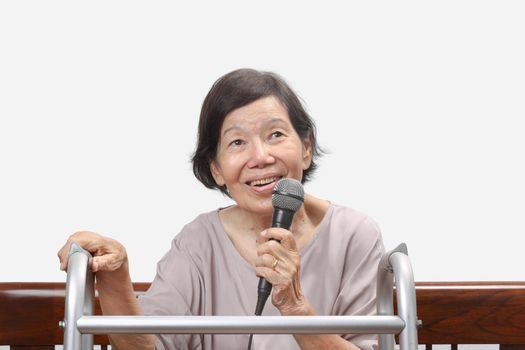 Elderly woman sing a song on microphone at home.