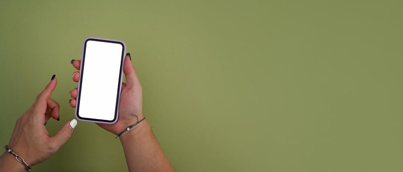 Mockup image of woman hand holding smart phone on green background with copy space.